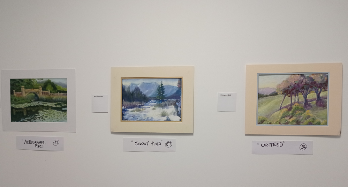Three landscape paintings on a white gallery wall