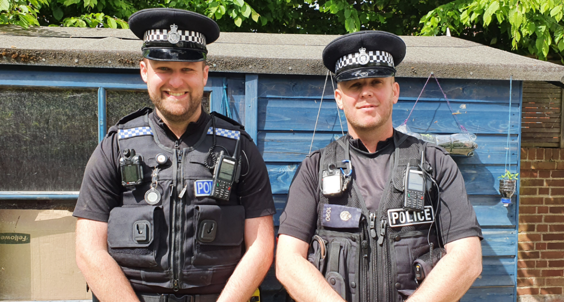 Two police officers standing next to each other smiling