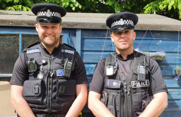 Two police officers standing next to each other smiling