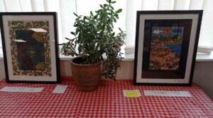 two paintings propped against a window resting on a checked tablecloth